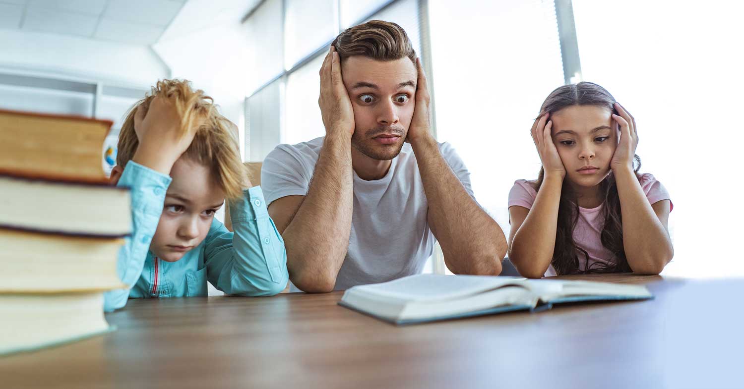 deux enfants et un adulte devant un livre, la tête dans les mains